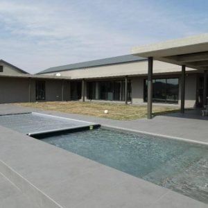 designer pool covers A house with a pool in front of it, featuring pool covers.