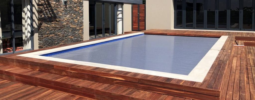 designer pool covers A pool with a wooden deck and pool covers.