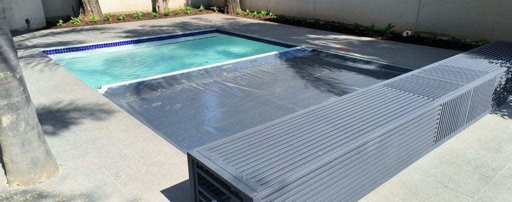 designer pool covers A backyard swimming pool with a pool cover for protection.