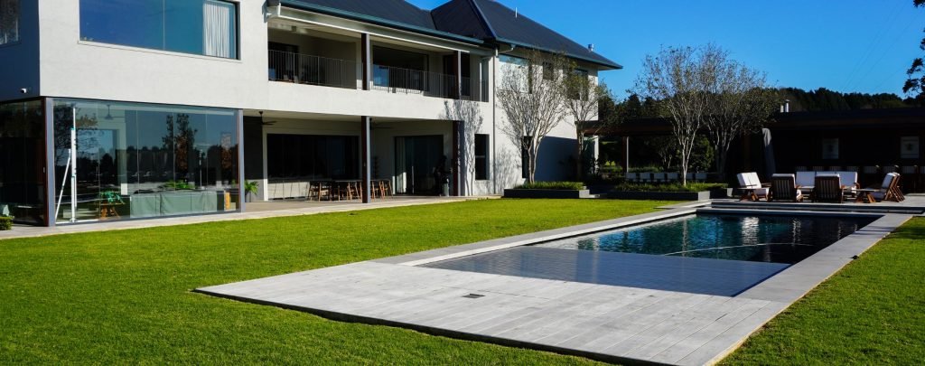 designer pool covers A house with a swimming pool in the backyard equipped with pool covers.