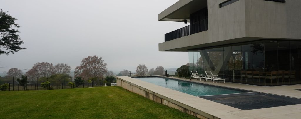 designer pool covers A modern house with a pool and pool covers.