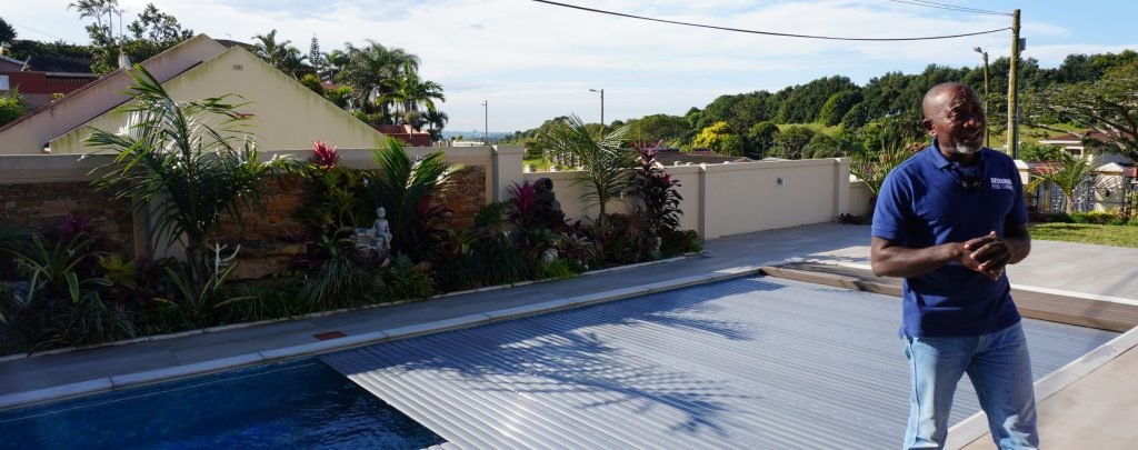 designer pool covers A man standing in front of a pool.